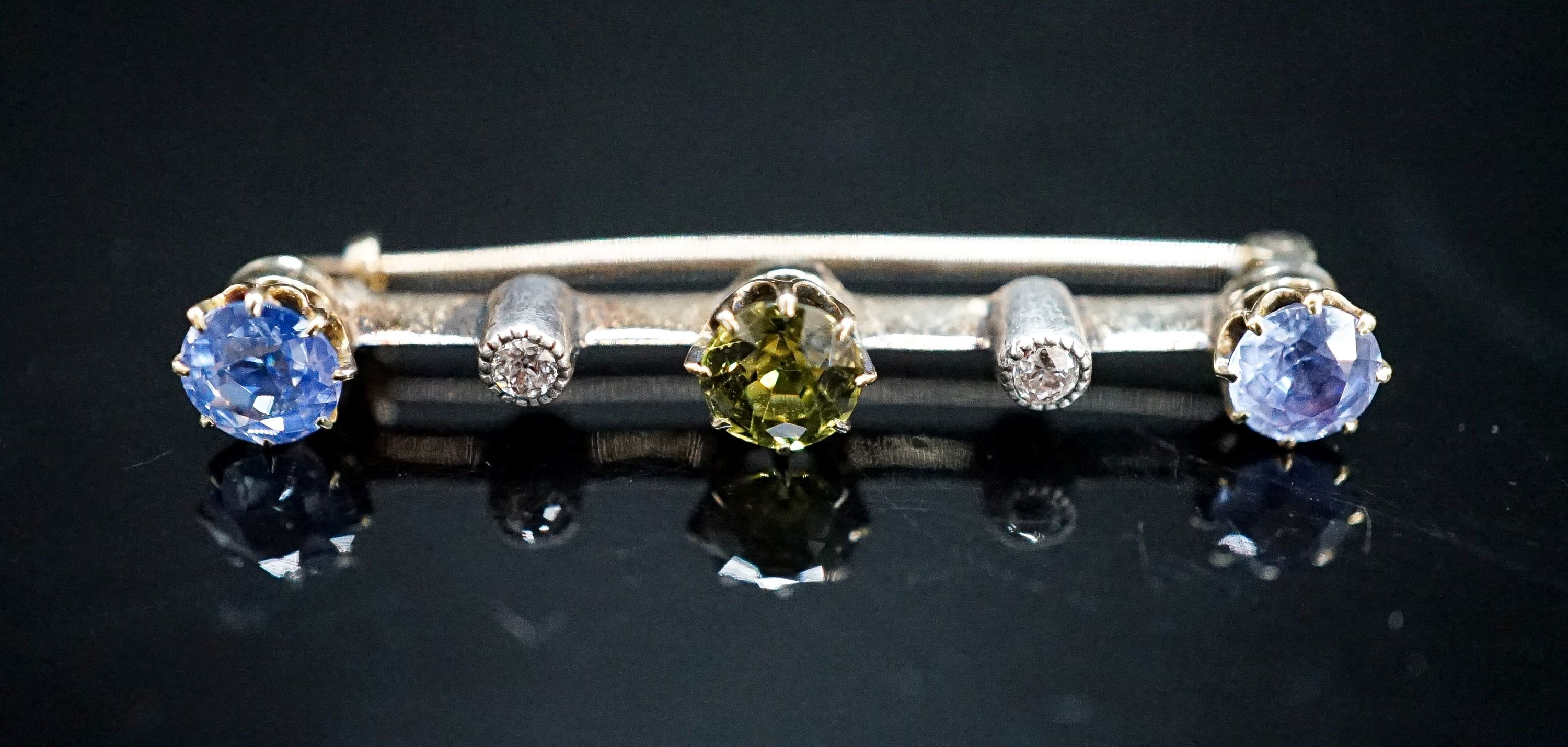 A yellow metal, single stone garnet?, two stone Ceylon sapphire and two stone diamond chip set bar brooch, 37mm, gross weight 2.8 grams.